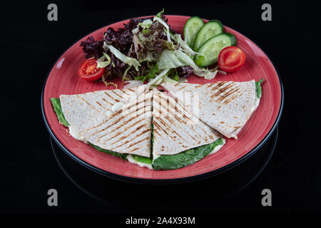 Türkische bazlama tost-gebackenes Brot getoastet mit Gemüse und Bratkartoffeln auf schwarzem Hintergrund serviert. Stockfoto