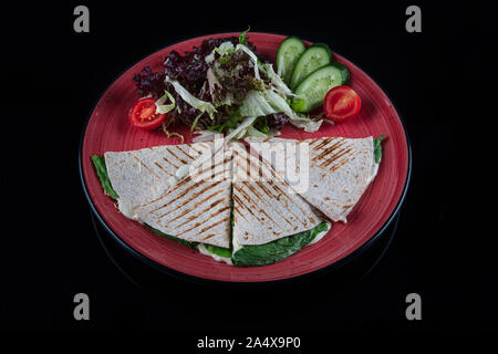 Türkische bazlama tost-gebackenes Brot getoastet mit Gemüse und Bratkartoffeln auf schwarzem Hintergrund serviert. Stockfoto