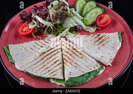 Türkische bazlama tost-gebackenes Brot getoastet mit Gemüse und Bratkartoffeln auf schwarzem Hintergrund serviert. Stockfoto