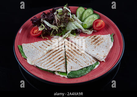 Türkische bazlama tost-gebackenes Brot getoastet mit Gemüse und Bratkartoffeln auf schwarzem Hintergrund serviert. Stockfoto