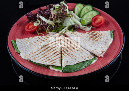 Türkische bazlama tost-gebackenes Brot getoastet mit Gemüse und Bratkartoffeln auf schwarzem Hintergrund serviert. Stockfoto