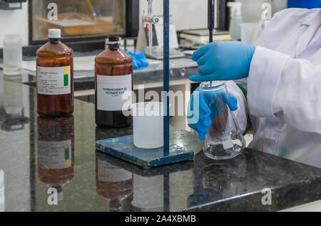 Frau Hände in schutzhandschuhen Reagenzglas in Händen halten produziert Chemie Test. Stockfoto