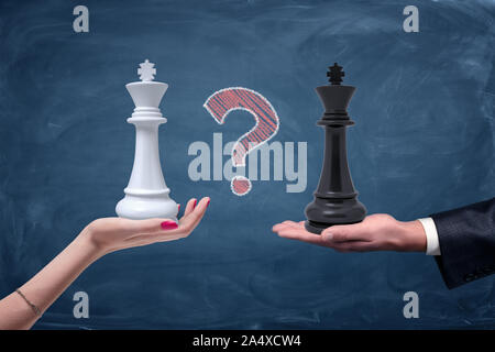 Ein Chalk Fragezeichen zwischen einem weiblichen Hand mit einem weißen chess King und eine männliche Hand mit einem schwarzen König. Stockfoto