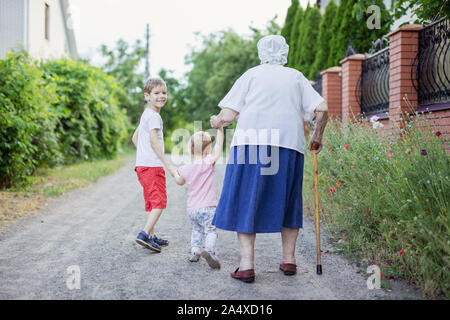 Jungen, Mädchen und ihre Großmutter zu Fuß die Straße runter in die Landschaft Stockfoto