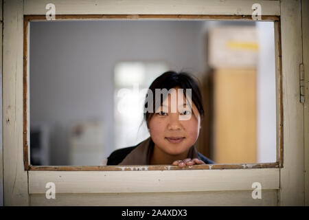 Portrait von Frau blickt durch bei Abstand an der Oberseite einer Tür. Stockfoto