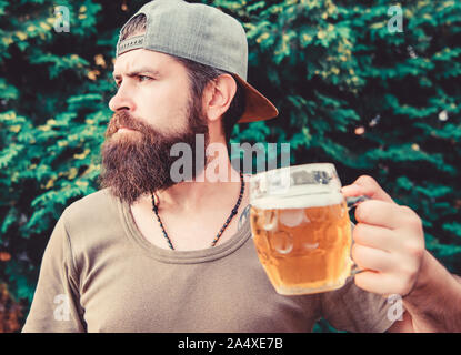 Die hipster Drink überhaupt. Hipster Mann mit Handwerk Bier am Tag. Hipster Trinker holding Bierkrug. Bärtige hipster genießen Sie Bier trinken auf die Natur. Entdecken Bier pong am Wochenende. Stockfoto