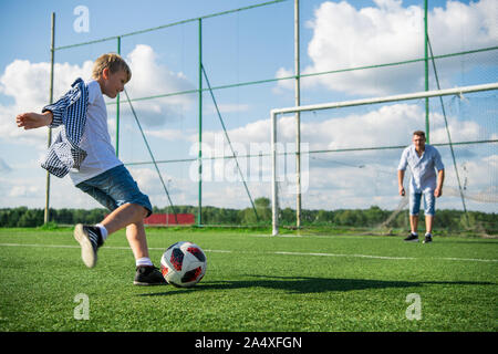 Lowsection von Vater mit Sohn Fußball auf der grünen Wiese. Stockfoto
