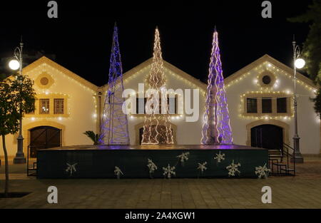 Schöne moderne Weihnachtsbaum, beleuchtet, dekoriert mit salbei auf der Straße in Larnaca, Zypern, vor klein, gemütlich beleuchteten Häuser, am Abend. Stockfoto