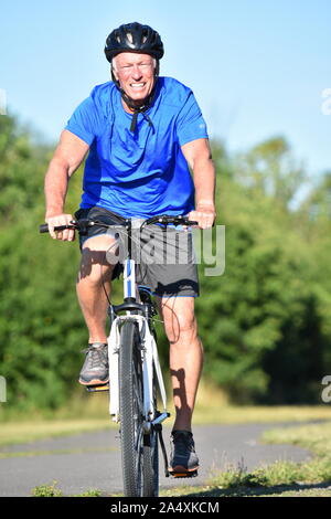 Lächelnd Athlet Rentner männliche Radfahrer tragen Helm Fahrrad fahren Stockfoto