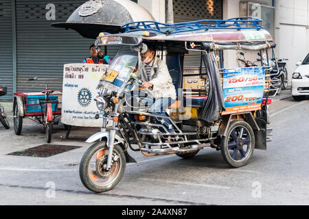 Mae Sot, Thailand - 3. Februar 2019: Ein typischer tuk tuk Laufwerke hinter einem Polizei. Dies ist die häufigste Form der Beförderung. Stockfoto