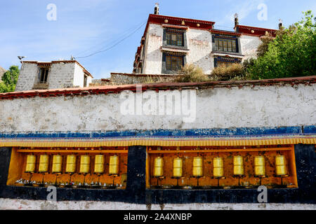 Eine Reihe von goldenen Gebetsmühlen schmücken Deprung Kloster in Lhasa, Tibet. Stockfoto