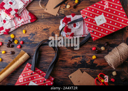 Geschenkboxen in Rot überprüft Papier gewickelt und die Inhalte eines Arbeitsbereichs aus. Flach. Valentinstag, Weihnachten oder Neujahr Geschenk verpacken Stockfoto