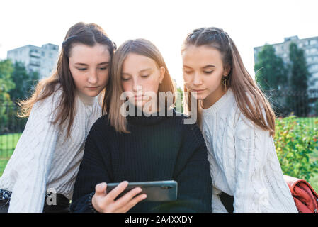 Drei Mädchen schoolgirls Freundin, schwere watching Film auf dem Smartphone. Sie lesen Soziale Netzwerke, Online Bewerbung im Internet. Im Sommer in der Stadt Stockfoto