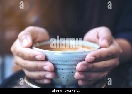 Closeup Bild der Hände halten eine Tasse heißen Kaffee auf Glas Tisch im Cafe Stockfoto