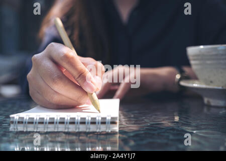 Closeup Bild der Frau Hand schreiben auf leeren Notebook mit Kaffeetasse auf dem Tisch Hintergrund Stockfoto