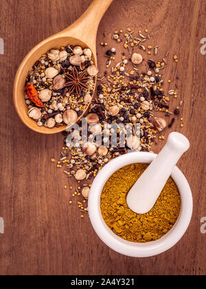 Verschiedene Gewürze in Löffel aus Holz, schwarzer Pfeffer, weißer Pfeffer, Schwarzer Senf, gelber Senf, Bockshornklee, Kümmel, Knoblauch und Fenchel Samen mit weißen Mor Stockfoto