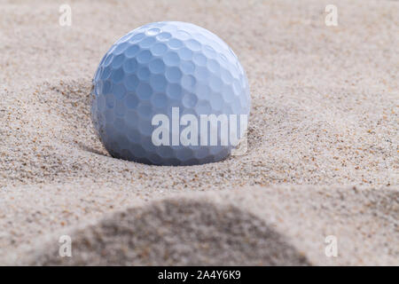 Golfball im Sandbunker geringe Schärfentiefe hautnah. Stockfoto