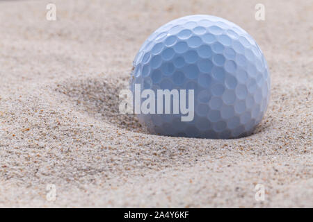 Golfball im Sandbunker geringe Schärfentiefe hautnah. Stockfoto