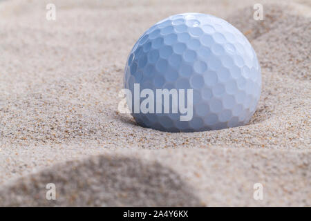 Golfball im Sandbunker geringe Schärfentiefe hautnah. Stockfoto