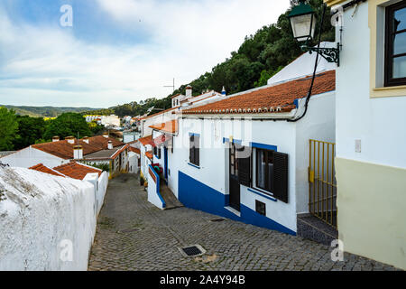 Bunte traditionelle Portugiesische gesäumt von Häusern entlang einer Straße mit Kopfsteinpflaster in Aljezur, in der Einer der pretties Dörfer der Costa Vicentina, Algarve, Portugal Stockfoto