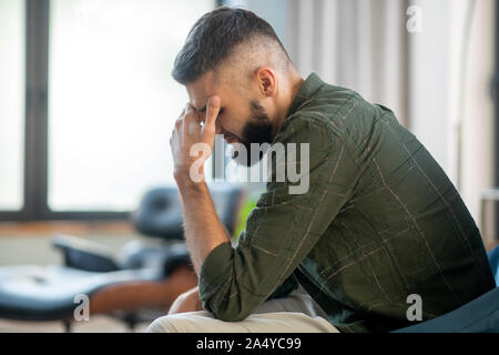 Mann sitzt in der Nähe der Fenster und wartet auf seinen psychoanalytiker Stockfoto