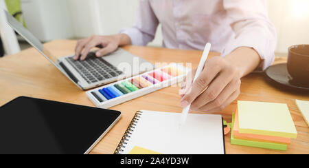 7/8 Schuß von jungen professionellen Designer Hobeln sein Projekt während der Verwendung von Laptops Stockfoto