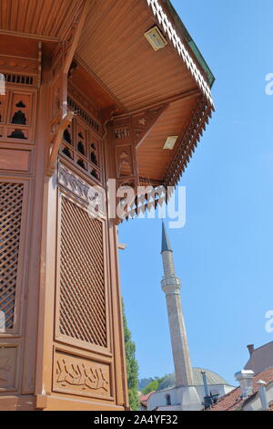 Details des hölzernen Brunnen Sebilj, der Hauptplatz von Bascarsija Bezirk, mit einem Minarett im Hintergrund, Sarajevo, Bosnien und Herzegowina Stockfoto