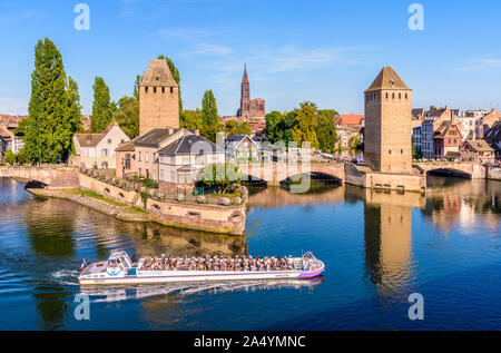 Die Ponts Couverts (überdachte Brücken) im Viertel Petite France und dem Straßburger Münster in der Entfernung mit einer Tour Boot Kreuzfahrt auf dem Fluss. Stockfoto