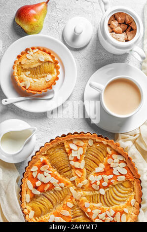 Französische Pear Tart, La Tarte Bourdaloue gefüllt mit pochierten Birnen und Frangipane oder mandelcreme auf einen konkreten Tisch mit einer Tasse Kakao serviert Drink ein Stockfoto