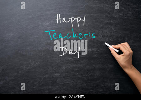 Bildung oder zurück Konzept zur Schule. Frau Hand, die Kreide mit Happy Lehrer Tag Text über der Tafel Hintergrund. Stockfoto