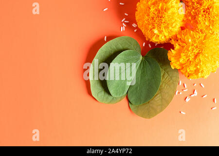 Happy Dussehra. Gelbe Blüten, grüne Blatt und Reis auf orangem Hintergrund. Dussehra Indian Festival Konzept. Stockfoto