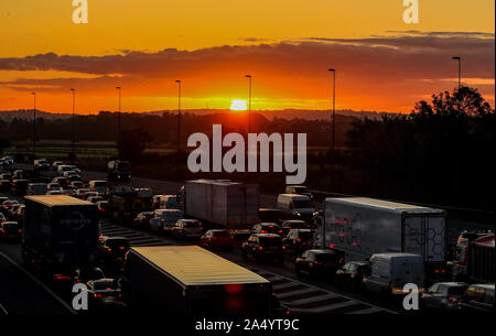 Die Sonne geht hinter dem Verkehr auf der M56 während des morgendlichen Berufsverkehrs in Cheshire. Stockfoto