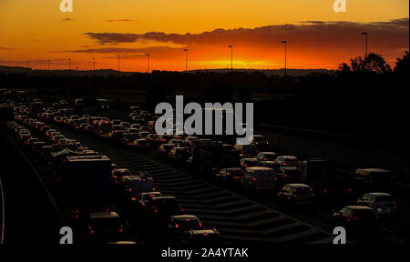 Die Sonne geht hinter dem Verkehr auf der M56 während des morgendlichen Berufsverkehrs in Cheshire. Stockfoto