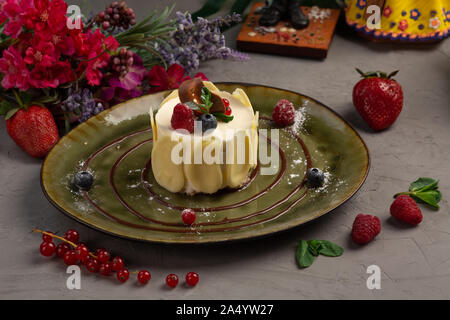 Dessert mit Sahne und Mandel Blüten in einer grünen Platine auf grauem Hintergrund Stockfoto
