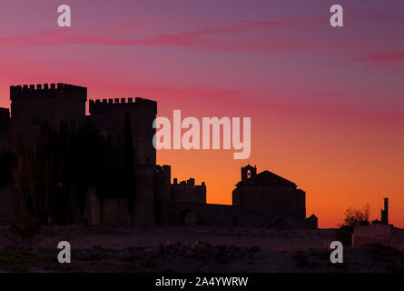 Bunte Himmel bei Sonnenuntergang mit Silhouetten einer mittelalterlichen Burg und eine Kirche in Ampudia, Spanien Stockfoto