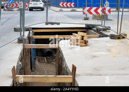 Engineering arbeitet. Reparatur des städtischen U-Kommunikation. Utility-Infrastruktur. Tiefes Loch bei der Verlegung. U-Rohr Installation. Stockfoto