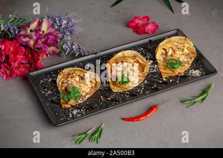 Pfannkuchen mit Julienne und mit grünen in einem schwarzen rechteckigen Platte auf einem grauen Hintergrund eingerichtet Stockfoto