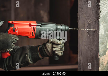 Mann bei der Arbeit, eine Bohrung mit großen Bohrer an einer Wand Stockfoto