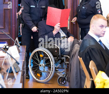 Hamburg, Deutschland. 17 Okt, 2019. Eine 93-jährige ehemalige SS-Bewachung der Konzentrationslager Stutthof bei Danzig ist in einem Gerichtssaal durch Gerichtsvollzieher sitzt in einem Rollstuhl am Landgericht geschoben. Die Staatsanwaltschaft wirft dem 93-jaehrigen Mann wegen Beihilfe zum Mord an 5230 Menschen. Der Beklagte war nur 17 oder 18 Jahre alt zum Zeitpunkt der Verbrechen. Das ist der Grund, warum der Prozess vor einem jugendkriminalität Kammer nimmt. Etwa 25 Überlebenden der Konzentrationslager erscheinen als Nebenkläger. Stockfoto