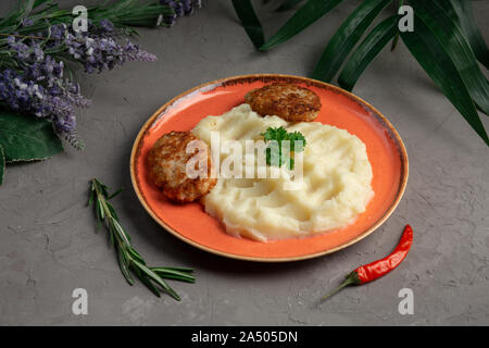 Gestampfte Kartoffeln und Fleisch Schnitzel in einem orange Platte auf grauem Hintergrund Stockfoto