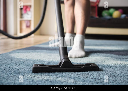 Staubsauger in Aktion. Mann Reinigung von Staub einen Teppich. Stockfoto