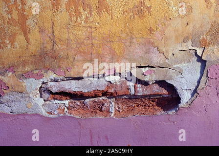Purpurrot und gelber Farbe, Gips Oberfläche auf Mauer eingerissen, crack Nahaufnahme Detail, Grunge horizontale schäbig Hintergrund Detail Nahaufnahme Stockfoto