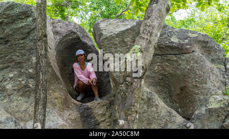 Asiatische Frau in Hut und rosa Pullover in Rock Hausbesetzung in großen Boulder Stockfoto