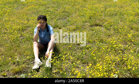 Jugendlich Mädchen mit Blumen mit geschlossenen Augen und Sitzen im großen Feld mit gelben Blumen Stockfoto