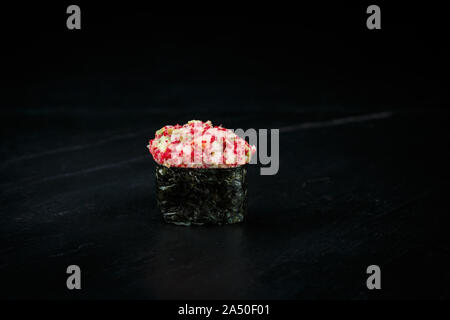 Japanische Küche single gunkan muki Ebi: fein gehackt Riesengarnelen mit Tobiko Kaviar, Avocado in Nori Blatt auf einem schwarzen Hintergrund gewickelt Stockfoto