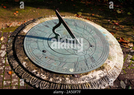 Stein und Metall Garten Sundial auf ein gesprenkelter Stein Garten Pfad Stockfoto