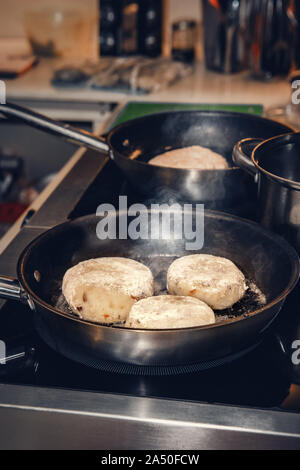Die Pfannkuchen aus den gekochten Kartoffeln und den Hüttenkäse werden in der Pfanne im Café gebraten. Nahaufnahme Stockfoto