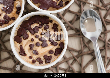 Leckeren, gesunden Dessert ohne schädliche Zusatzstoffe. Raw Banane Eiscreme mit Kokosnuss, beschichtet mit natürlichen Schokolade, in einem White Paper Cups mit Stockfoto