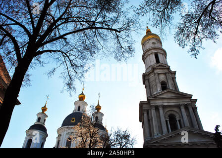 Annahme oder 1352 Kathedrale (Orthodoxe Kirche) von Charkow, Ukraine, Wintertag mit blauen bewölkten Himmel und schwarzen Baum Silhouette ohne Blätter Stockfoto