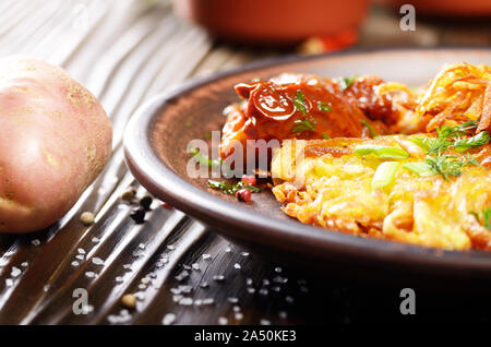 Detailansicht auf Hausgemachte leckere Kartoffelpuffer in Ton Teller mit getrockneten Tomaten Stockfoto
